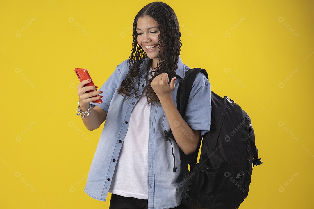 Jovem estudante com camisa jeans e com celular e mochila