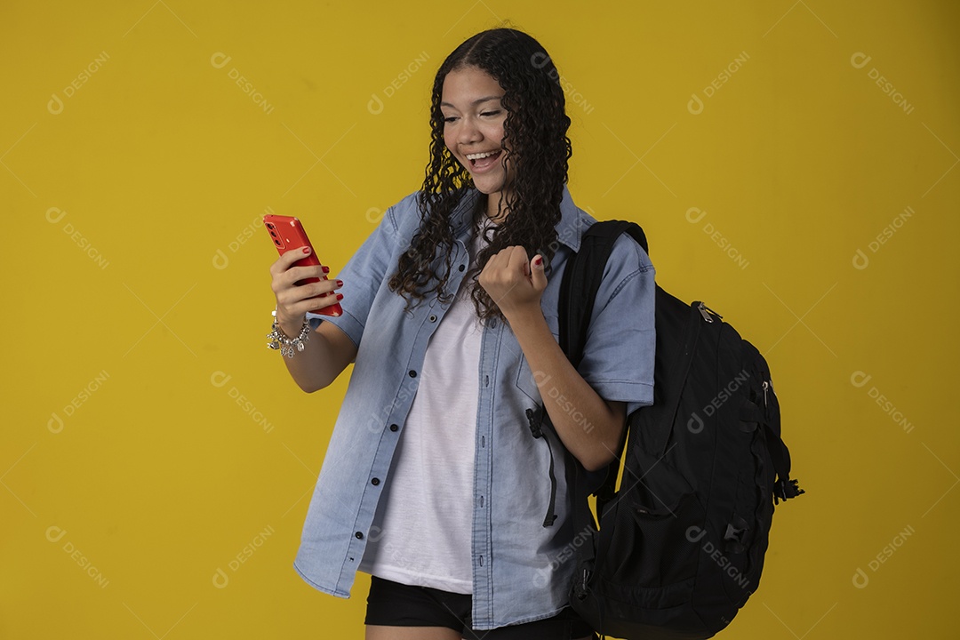 Jovem estudante com camisa jeans e com celular e mochila