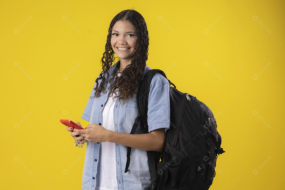 Jovem estudante com camisa jeans e com celular e mochila