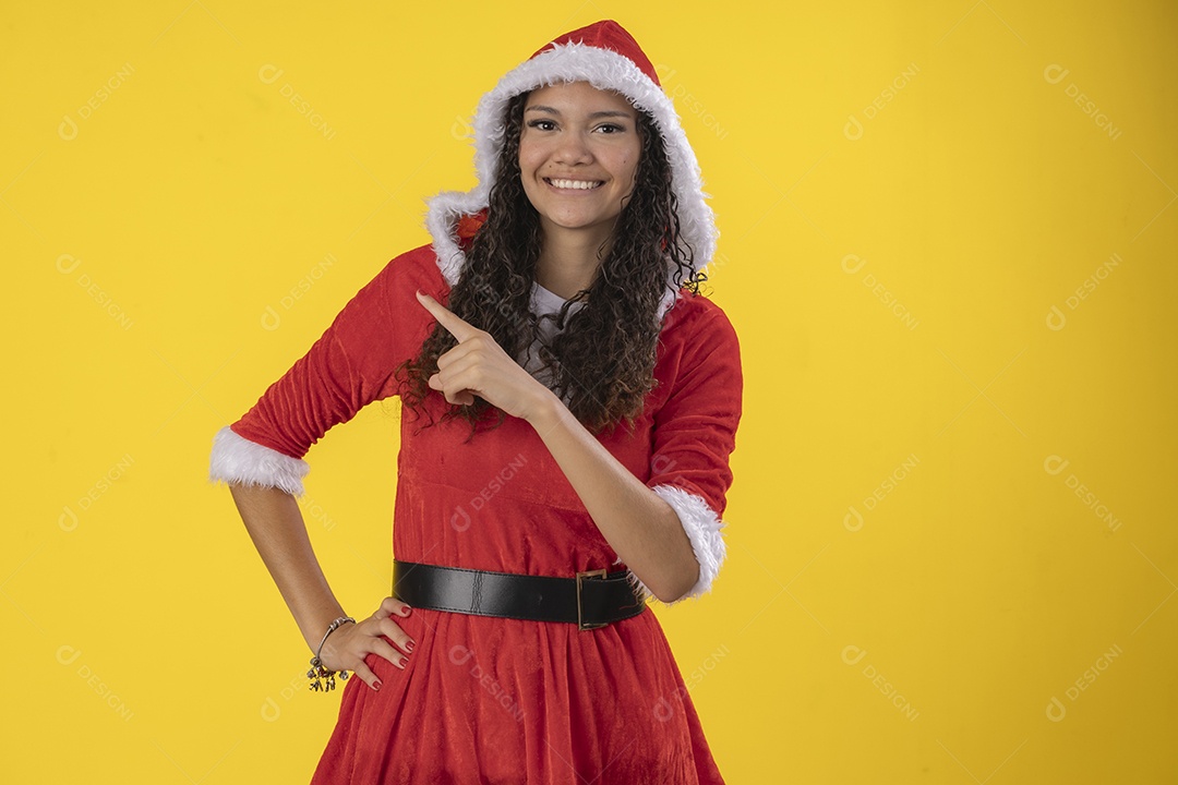 Jovem com fantasia de mamãe noel apontando para lado