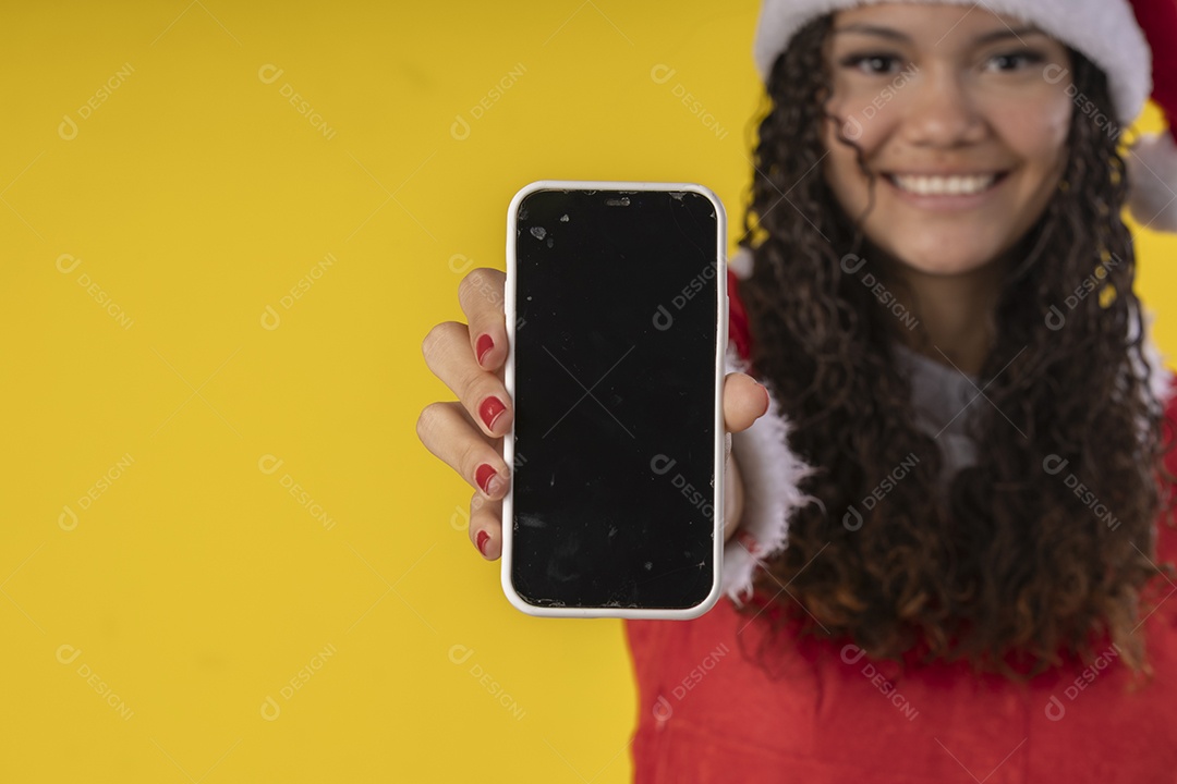 Uma jovem vestida de mamãe noel com um celular nas mãos