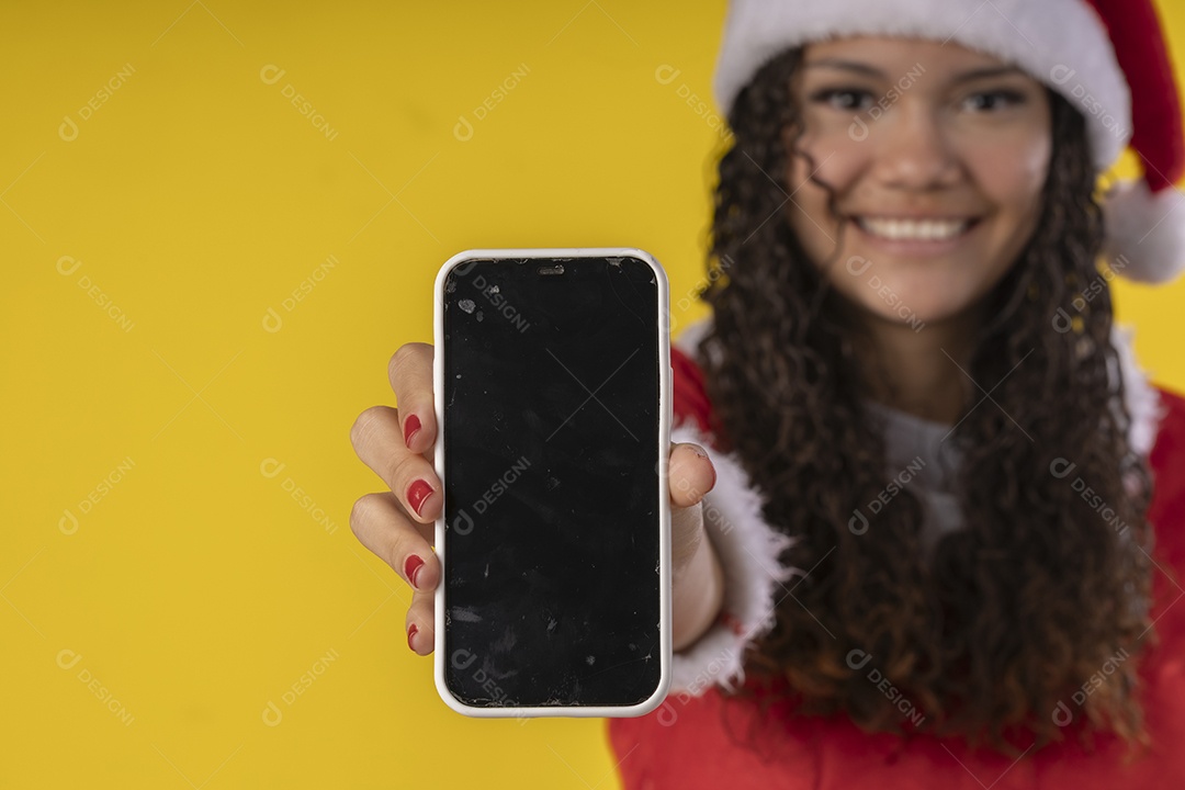 Jovem vestida de mamãe noel com celular nas mão