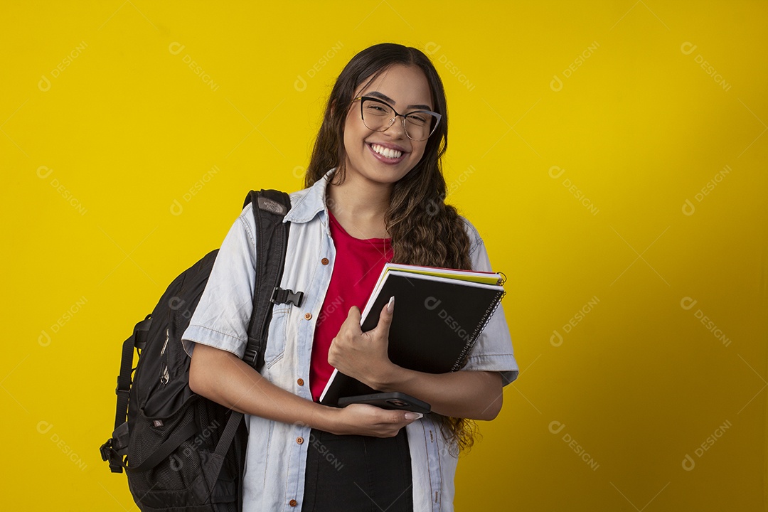 Jovem feliz segurando livros e com mochila nas costa