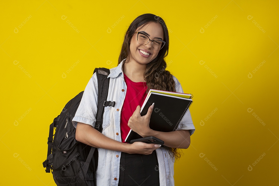 Jovem feliz segurando livros e com mochila nas costa