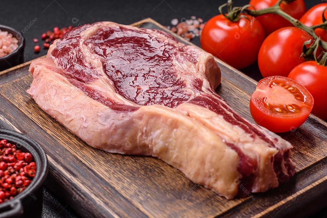 Carne sobre tábua de madeira com tomates e temperos