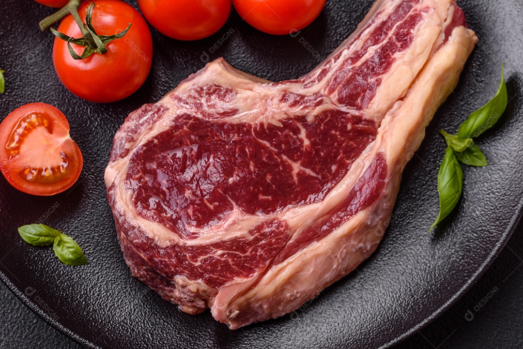 Pedaço de bife com tomates e ervas sobre prato para preparo