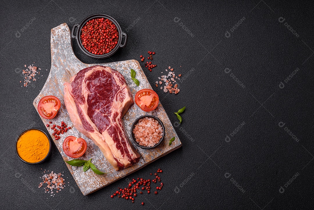 Bife de carne crua com temperos ao lado sobre tábua de madeira