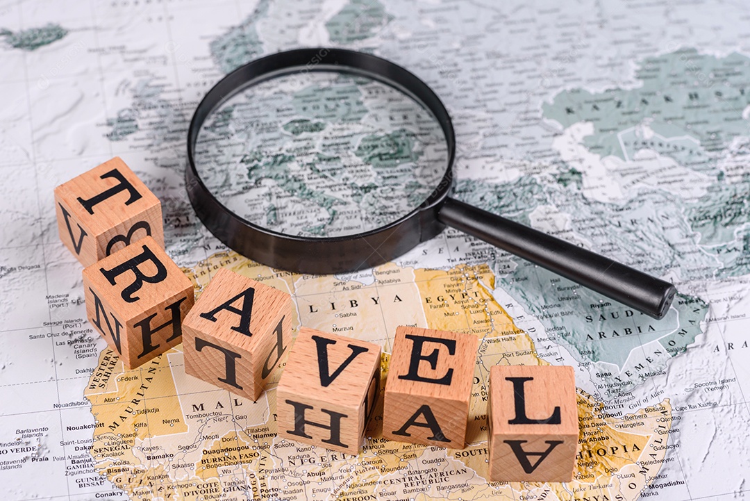 Blocos de madeira escrito viagem sobre fundo lupa mapa mundial