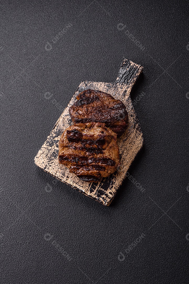 Bife fresco, suculento e delicioso em um fundo escuro. Prato de carne com especiarias e ervas