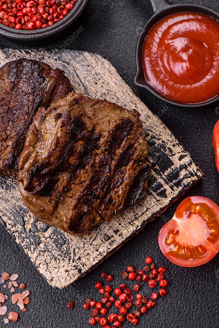 Bife fresco, suculento e delicioso em um fundo escuro. Prato de carne com especiarias e ervas