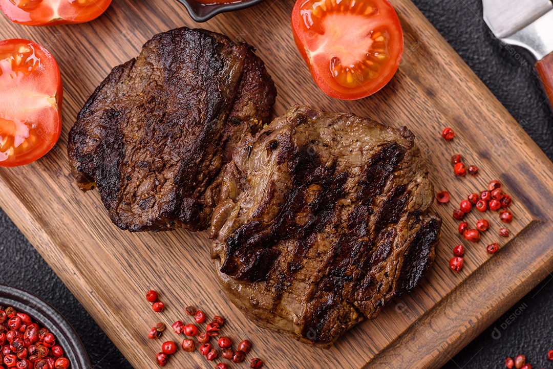 Bife fresco, suculento e delicioso em um fundo escuro. Prato de carne com especiarias e ervas