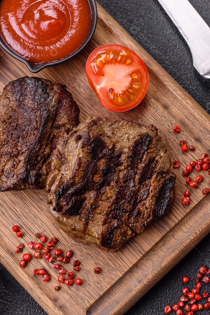 Bife fresco, suculento e delicioso em um fundo escuro. Prato de carne com especiarias e ervas