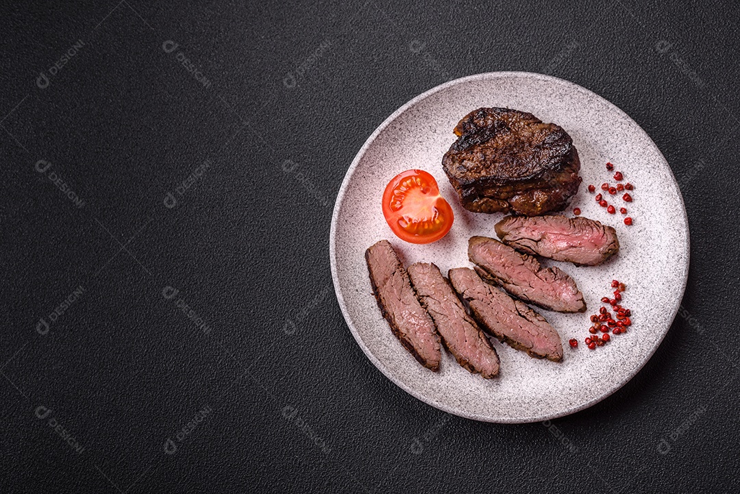 Bife fresco, suculento e delicioso em um fundo escuro. Prato de carne com especiarias e ervas