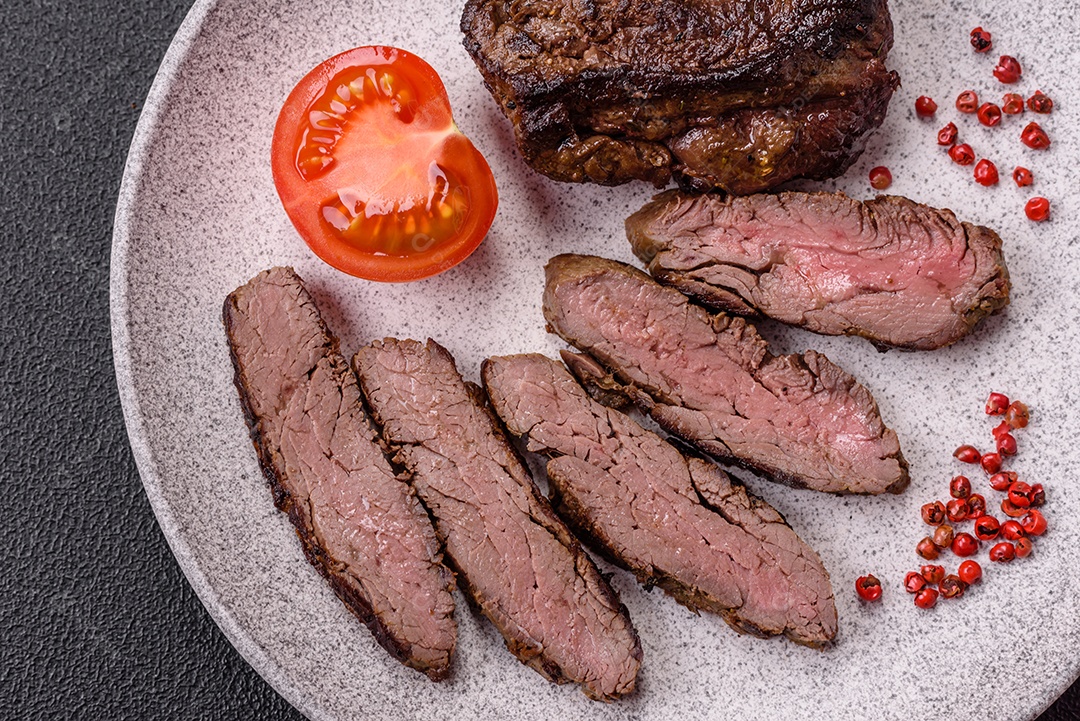 Bife fresco, suculento e delicioso em um fundo escuro. Prato de carne com especiarias e ervas