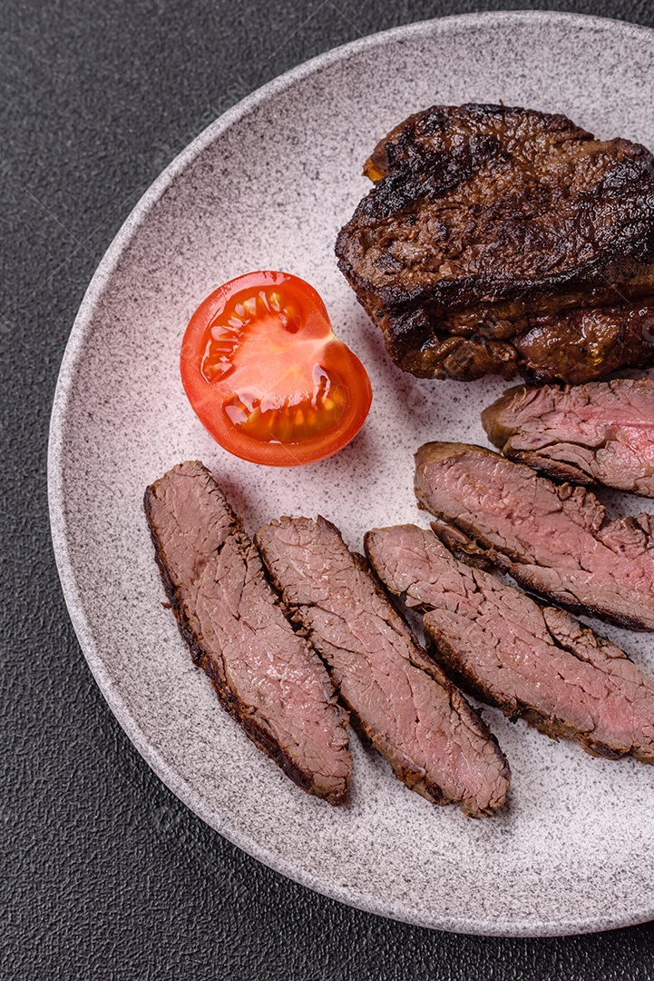 Bife fresco, suculento e delicioso em um fundo escuro. Prato de carne com especiarias e ervas