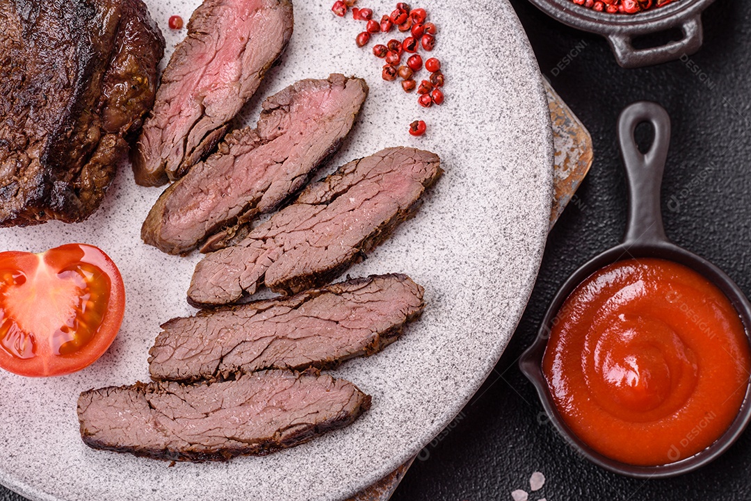 Bife fresco, suculento e delicioso em um fundo escuro. Prato de carne com especiarias e ervas