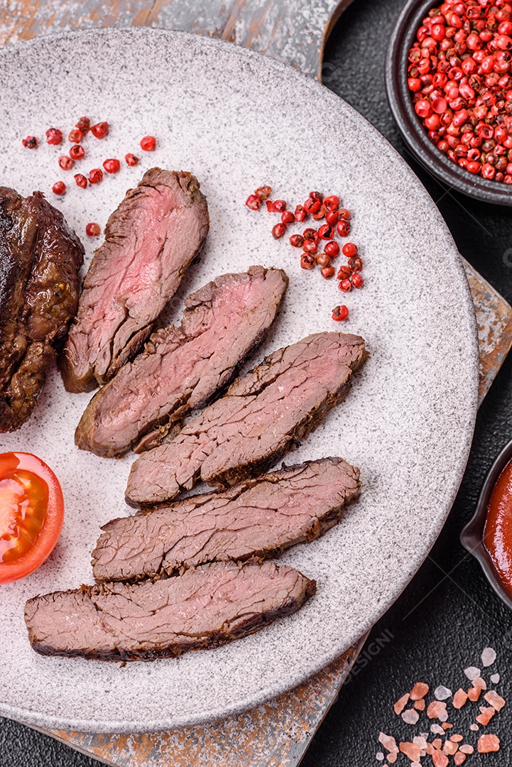 Bife fresco, suculento e delicioso em um fundo escuro. Prato de carne com especiarias e ervas