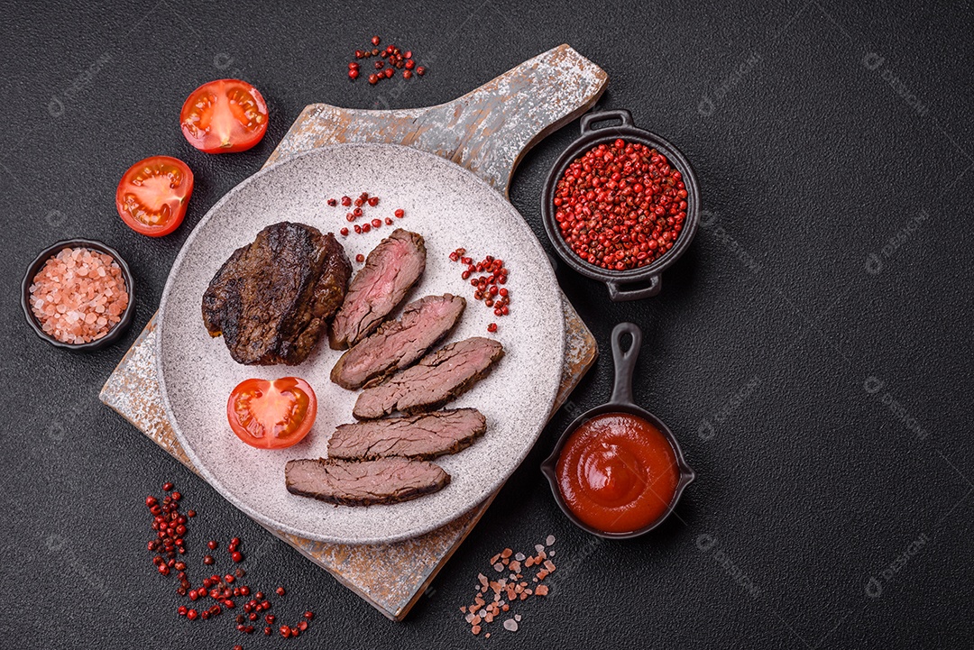 Bife fresco, suculento e delicioso em um fundo escuro. Prato de carne com especiarias e ervas