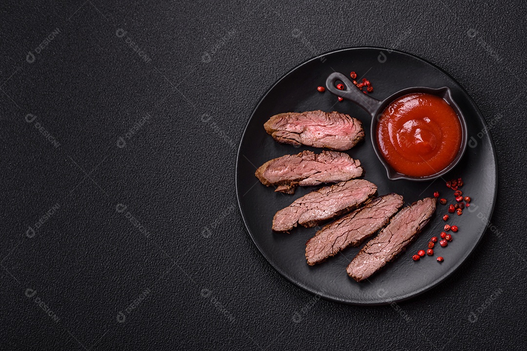 Bife fresco, suculento e delicioso em um fundo escuro. Prato de carne com especiarias e ervas