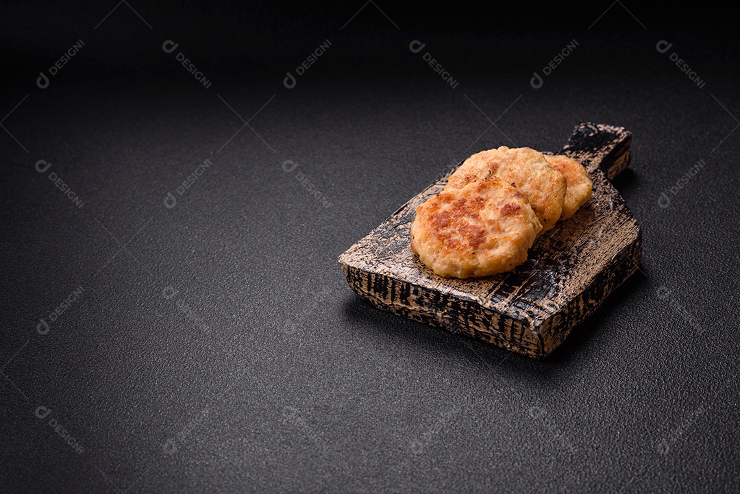 Deliciosas costeletas de peixe picado frito fresco com especiarias e ervas sobre um fundo escuro de concreto