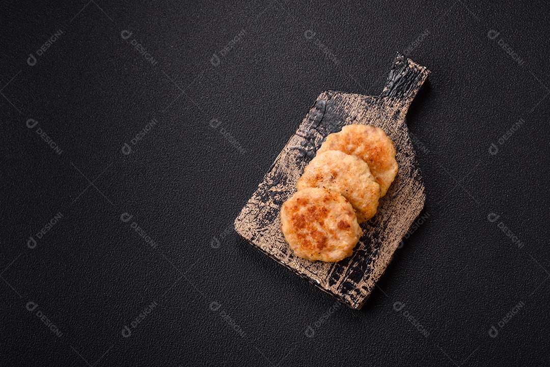 Deliciosas costeletas de peixe picado frito fresco com especiarias e ervas sobre um fundo escuro de concreto