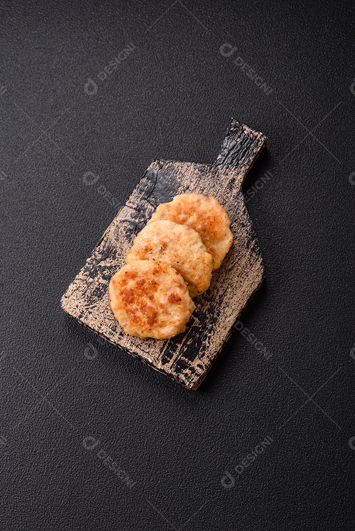 Deliciosas costeletas de peixe picado frito fresco com especiarias e ervas sobre um fundo escuro de concreto