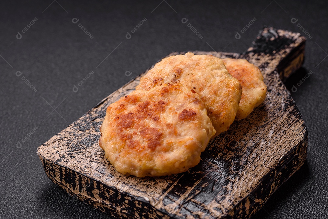Deliciosas costeletas de peixe picado frito fresco com especiarias e ervas sobre um fundo escuro de concreto