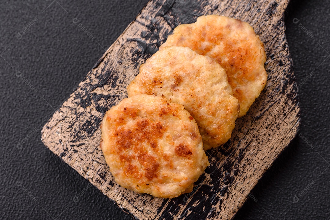 Deliciosas costeletas de peixe picado frito fresco com especiarias e ervas sobre um fundo escuro de concreto