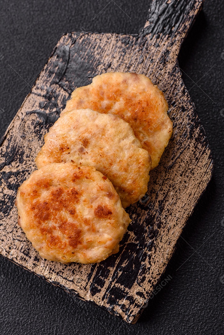 Deliciosas costeletas de peixe picado frito fresco com especiarias e ervas sobre um fundo escuro de concreto