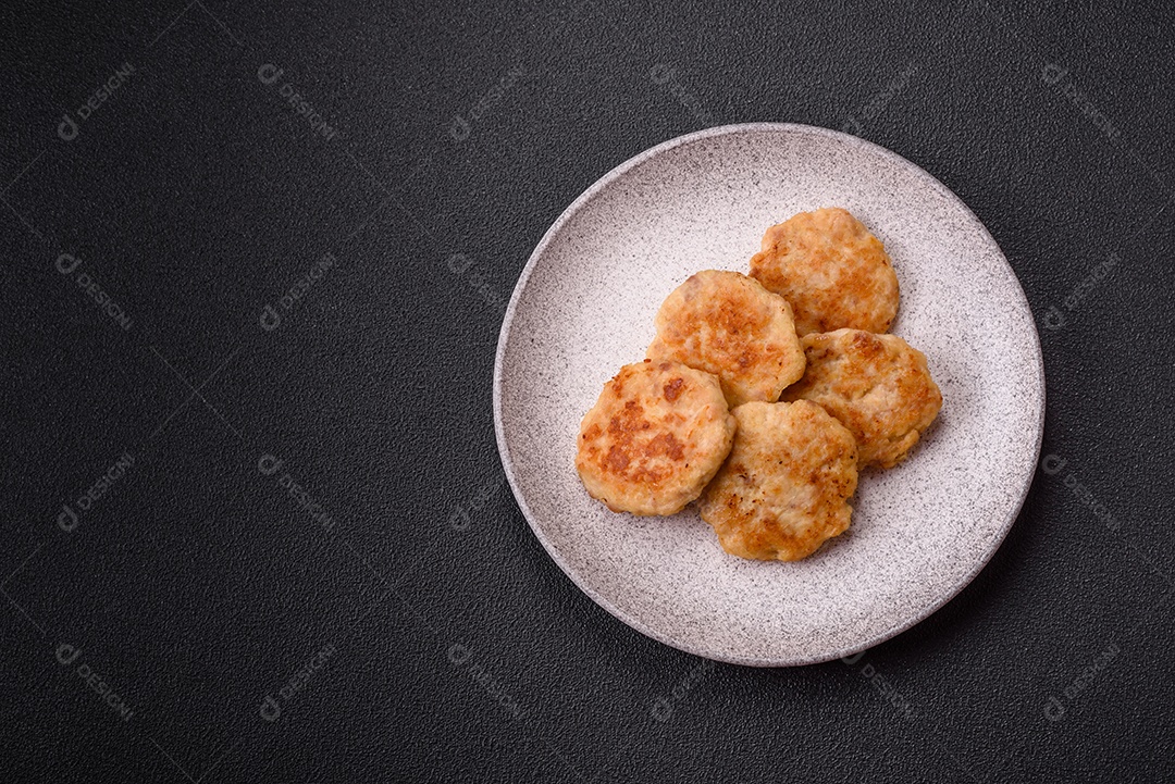 Deliciosas costeletas de peixe picado frito fresco com especiarias e ervas sobre um fundo escuro de concreto