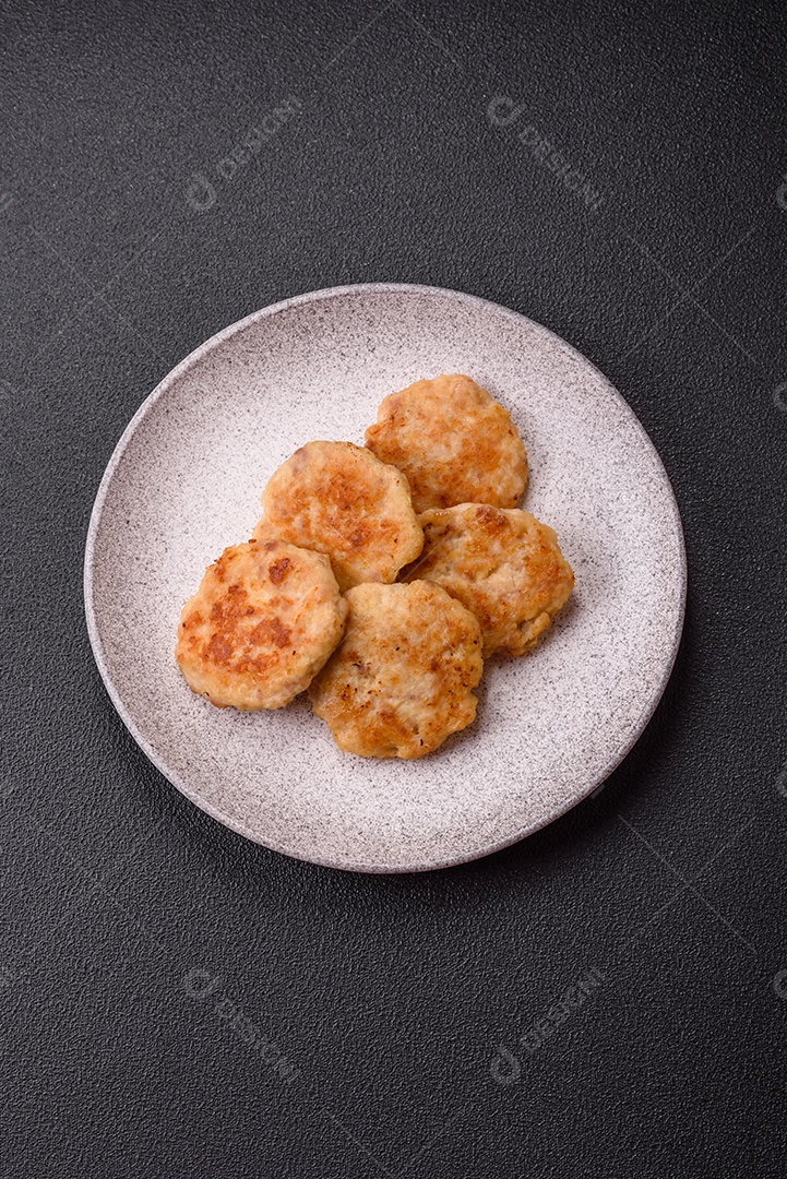 Deliciosas costeletas de peixe picado frito fresco com especiarias e ervas sobre um fundo escuro de concreto