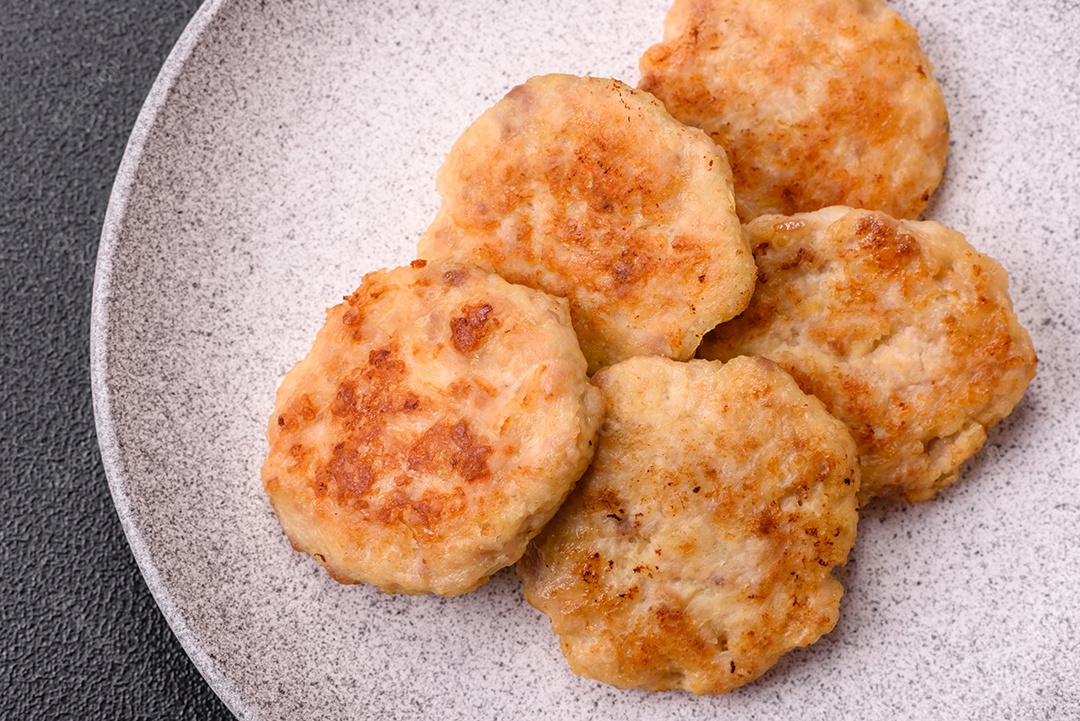Deliciosas costeletas de peixe picado frito fresco com especiarias e ervas sobre um fundo escuro de concreto