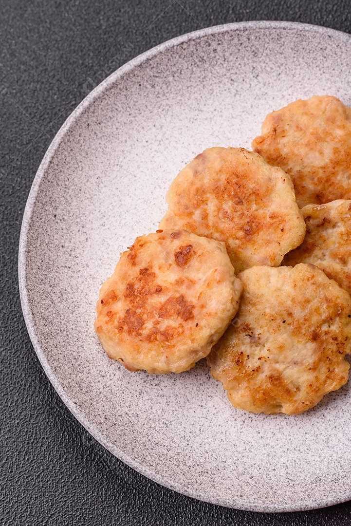 Deliciosas costeletas de peixe picado frito fresco com especiarias e ervas sobre um fundo escuro de concreto