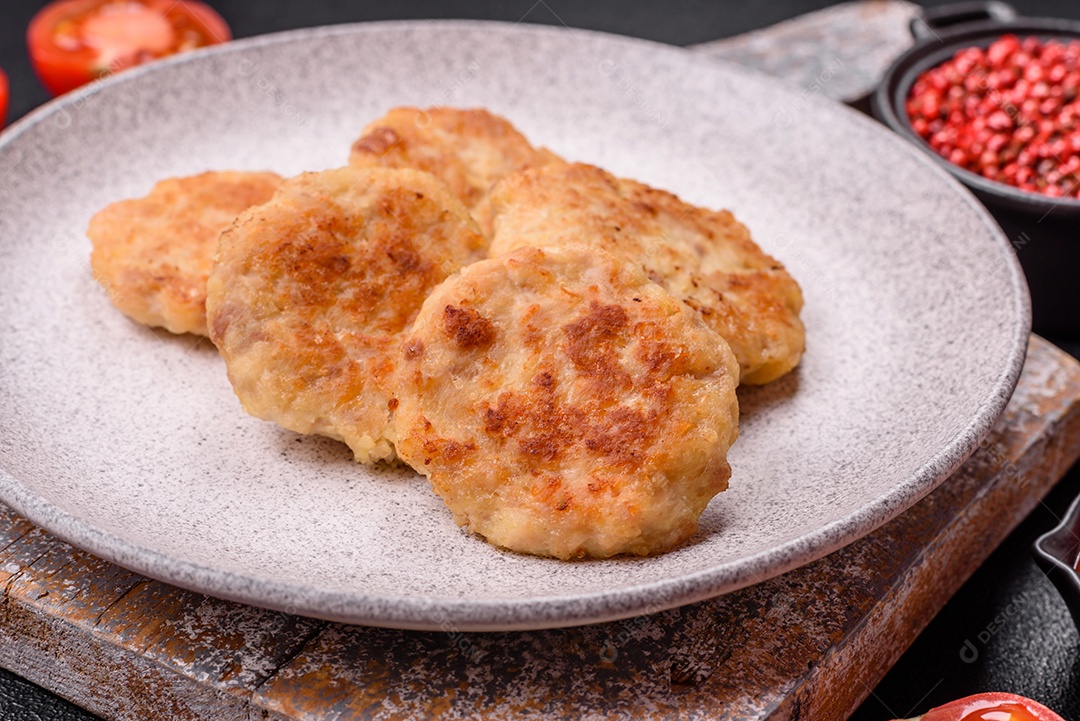 Deliciosas costeletas de peixe picado frito fresco com especiarias e ervas sobre um fundo escuro de concreto