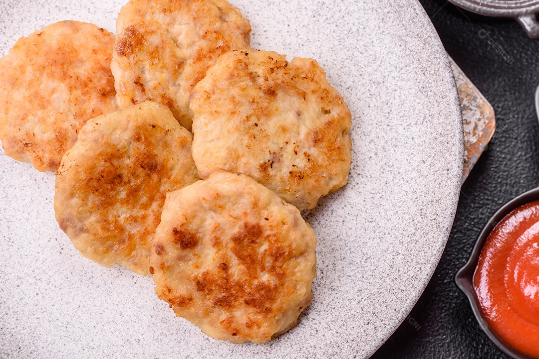 Deliciosas costeletas de peixe picado frito fresco com especiarias e ervas sobre um fundo escuro de concreto