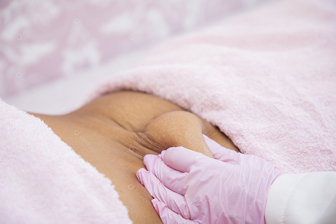 Esteticista pegando na barriga de paciente para tratamento