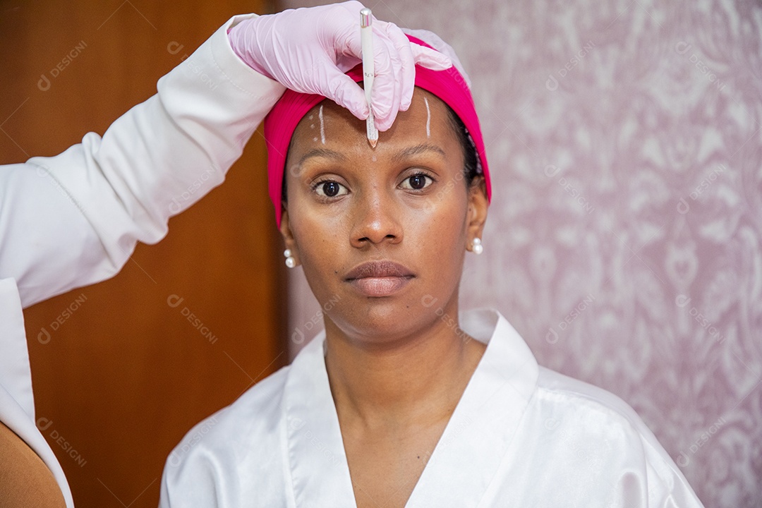 Esteticista aplicando marcações no rosto de paciente