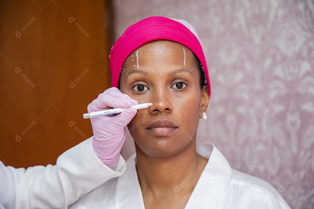 Esteticista fazendo marcação no rosto de paciente