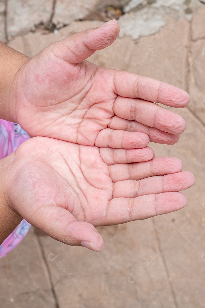 As mãos da menina enrugam os dedos enrugados
