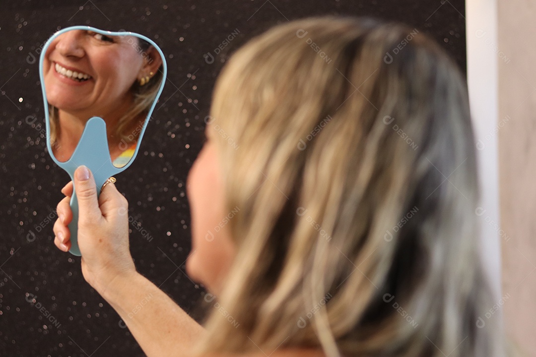 Bela mulher branca sorridente se olhando em espelho sobre fundo isolado