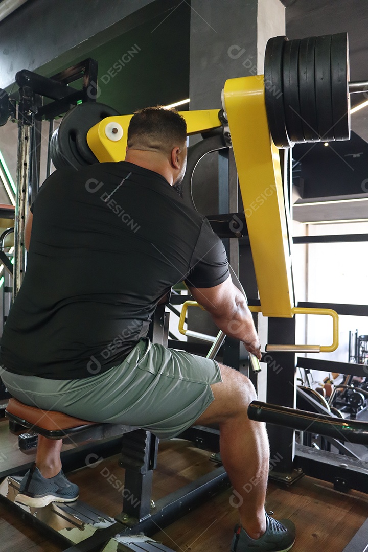 Belo homem fazendo exercicíos sobre uma academia