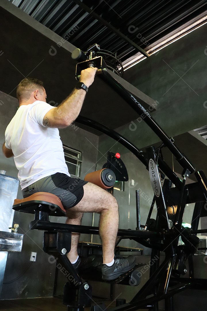 Belo homem fazendo exercicíos sobre uma academia