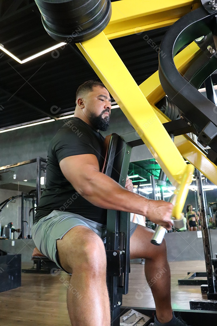 Belo homem fazendo exercicíos sobre uma academia