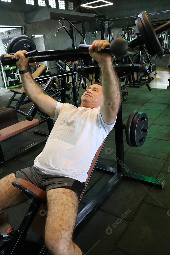 Belo homem fazendo exercicíos sobre uma academia