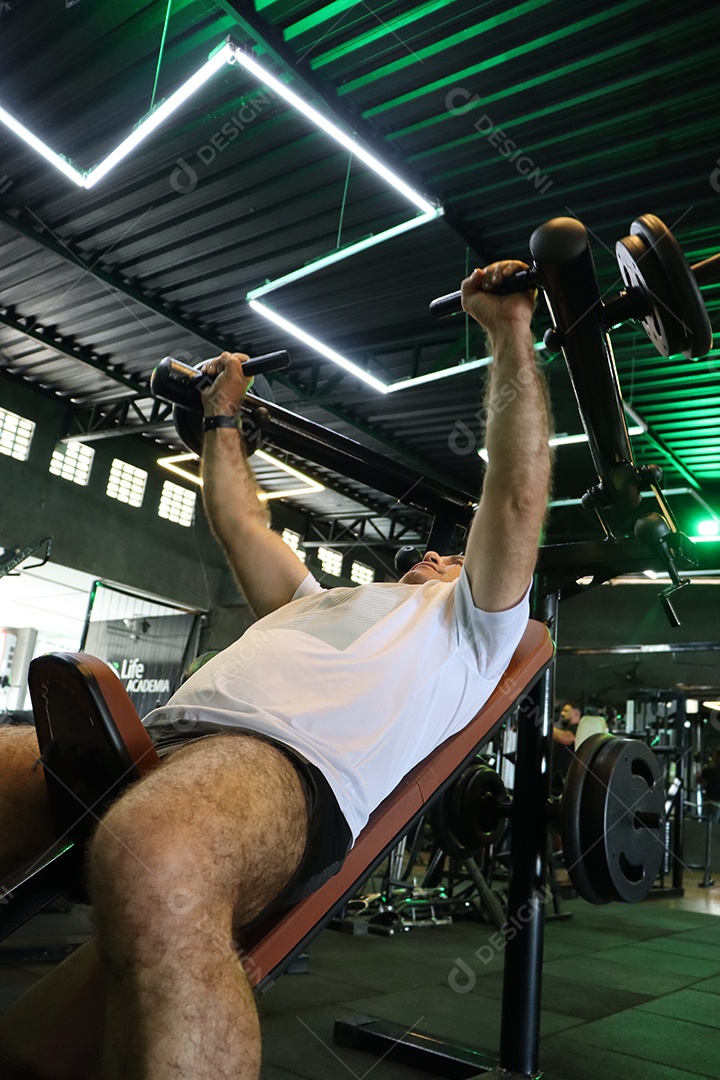 Belo homem fazendo exercicíos sobre uma academia