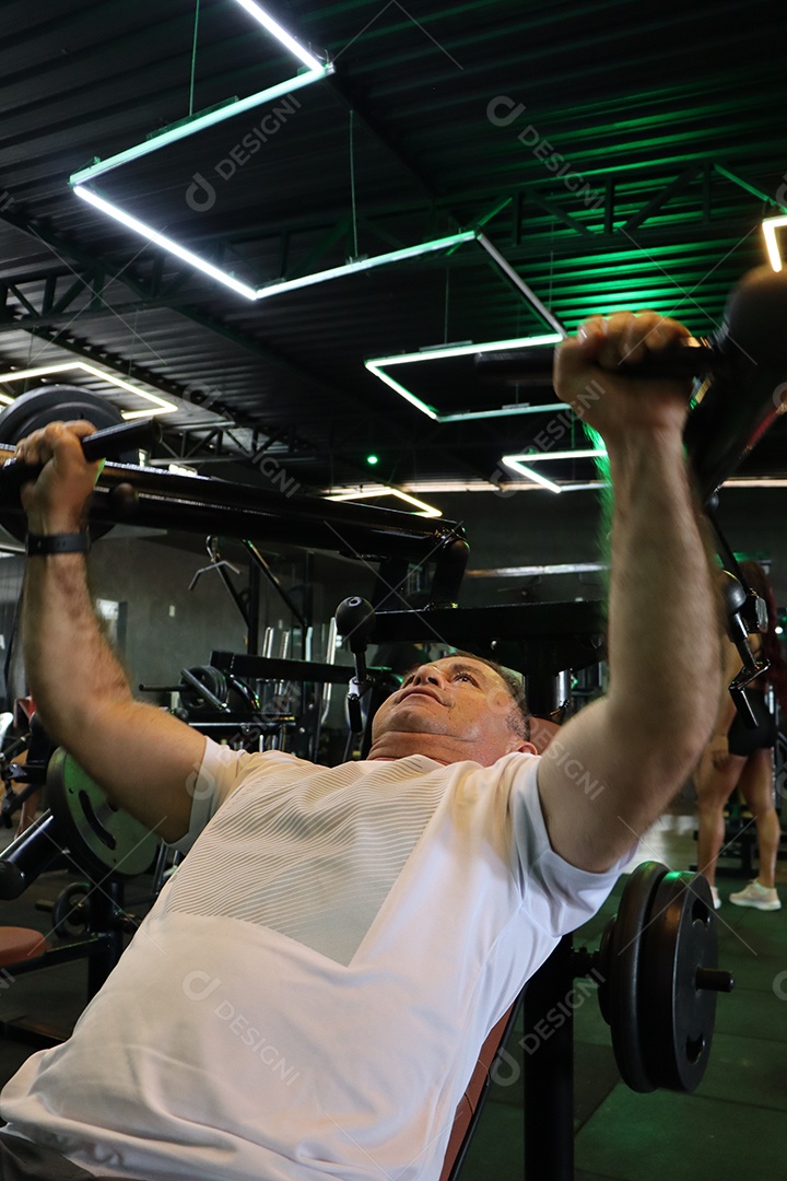 Belo homem fazendo exercicíos sobre uma academia