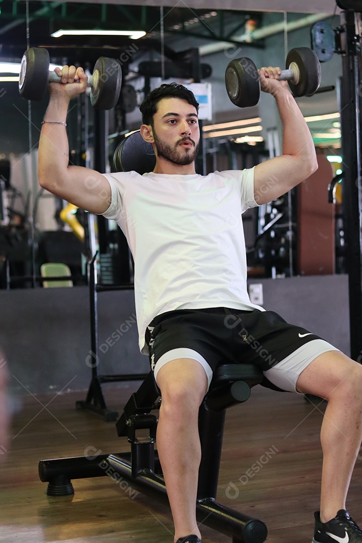 Belo homem fazendo exercicíos sobre uma academia
