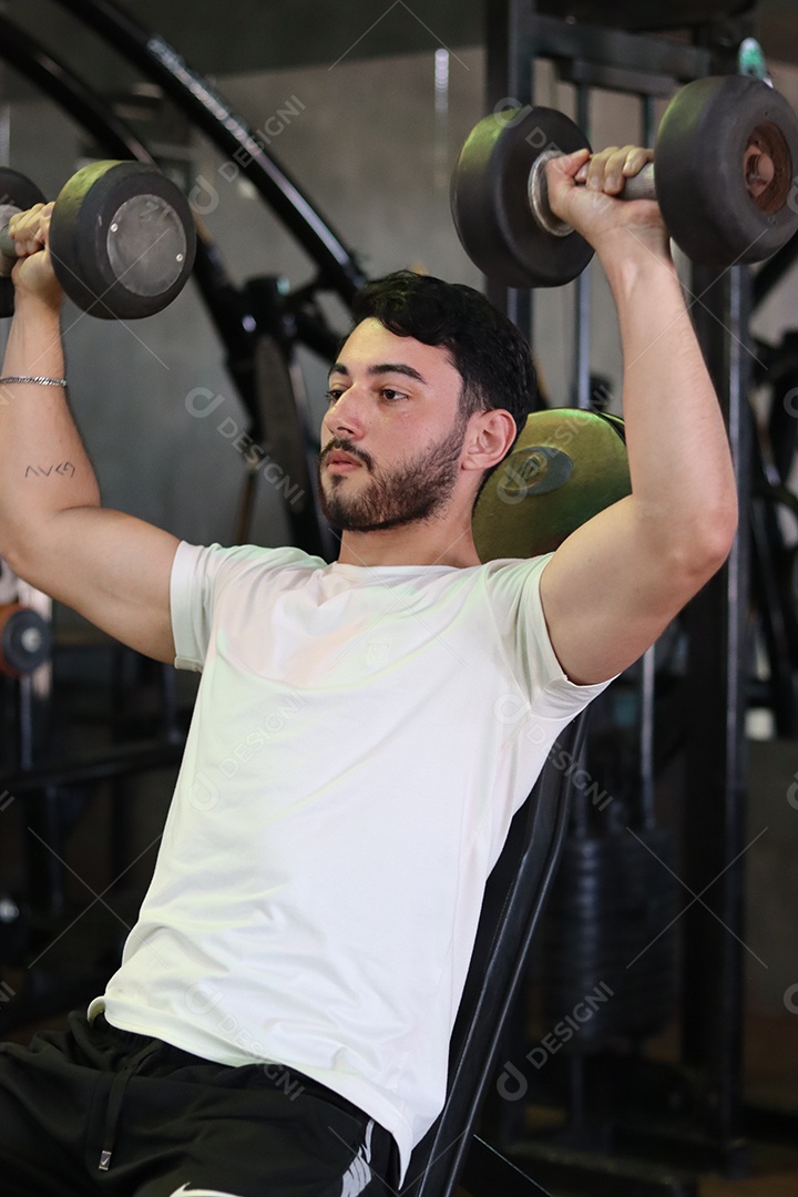 Belo homem fazendo exercicíos sobre uma academia