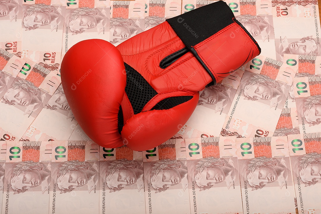 Luva de box vermelha sobre notas de dinheiro