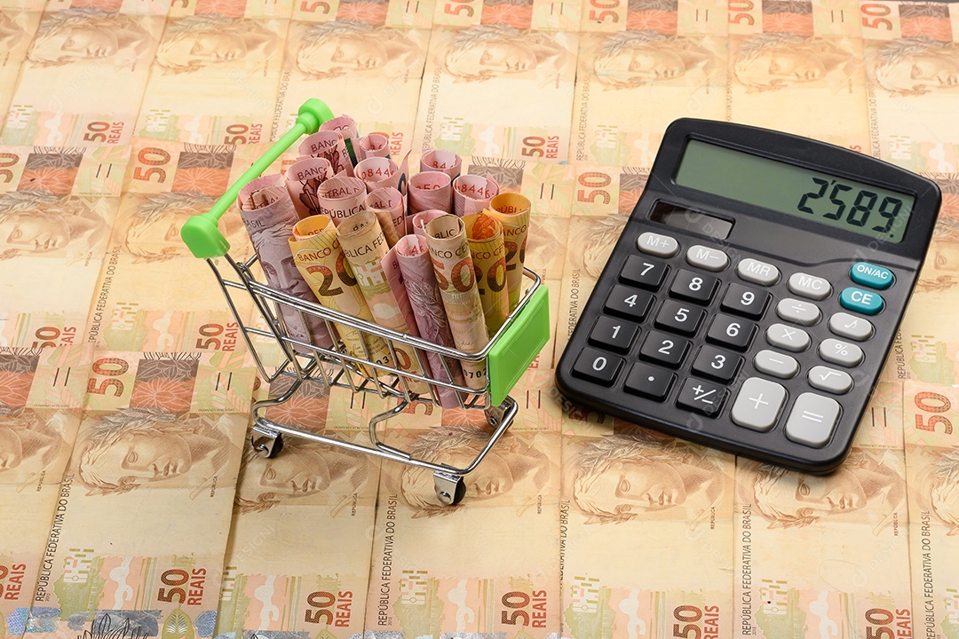 Calculadora sobre notas de dinheiro e carrinho de compra com notas de dinheiro
